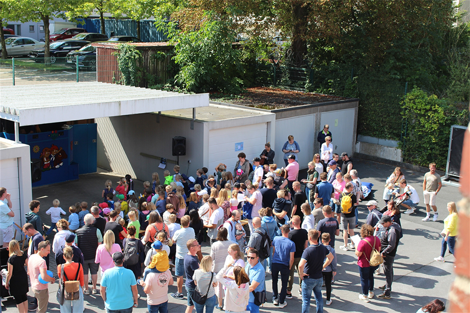 Carport und Garagen, Personen auf Bänken, Puppenbühne im Carport