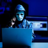 Anonymer Anrufer mit Maske am Computer