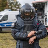 Entschärfer im Entschärferanzug vor Polizeifahrzeug