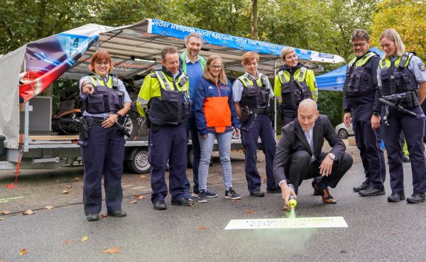 Polizeipräsident Tim Frommeyer sprüht im Beisein von Beteiligten den Spruch "Verantwortung stoppt Vollgas" auf den Asphalt. Foto: Polizei Gelsenkirchen